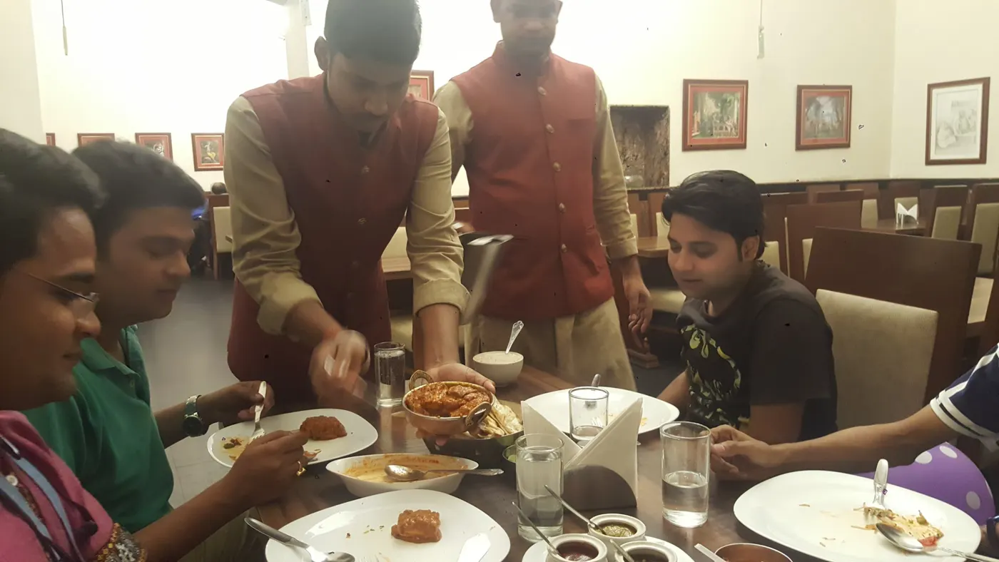 A team dinner at a restaurant in India, a waiter serving a curry