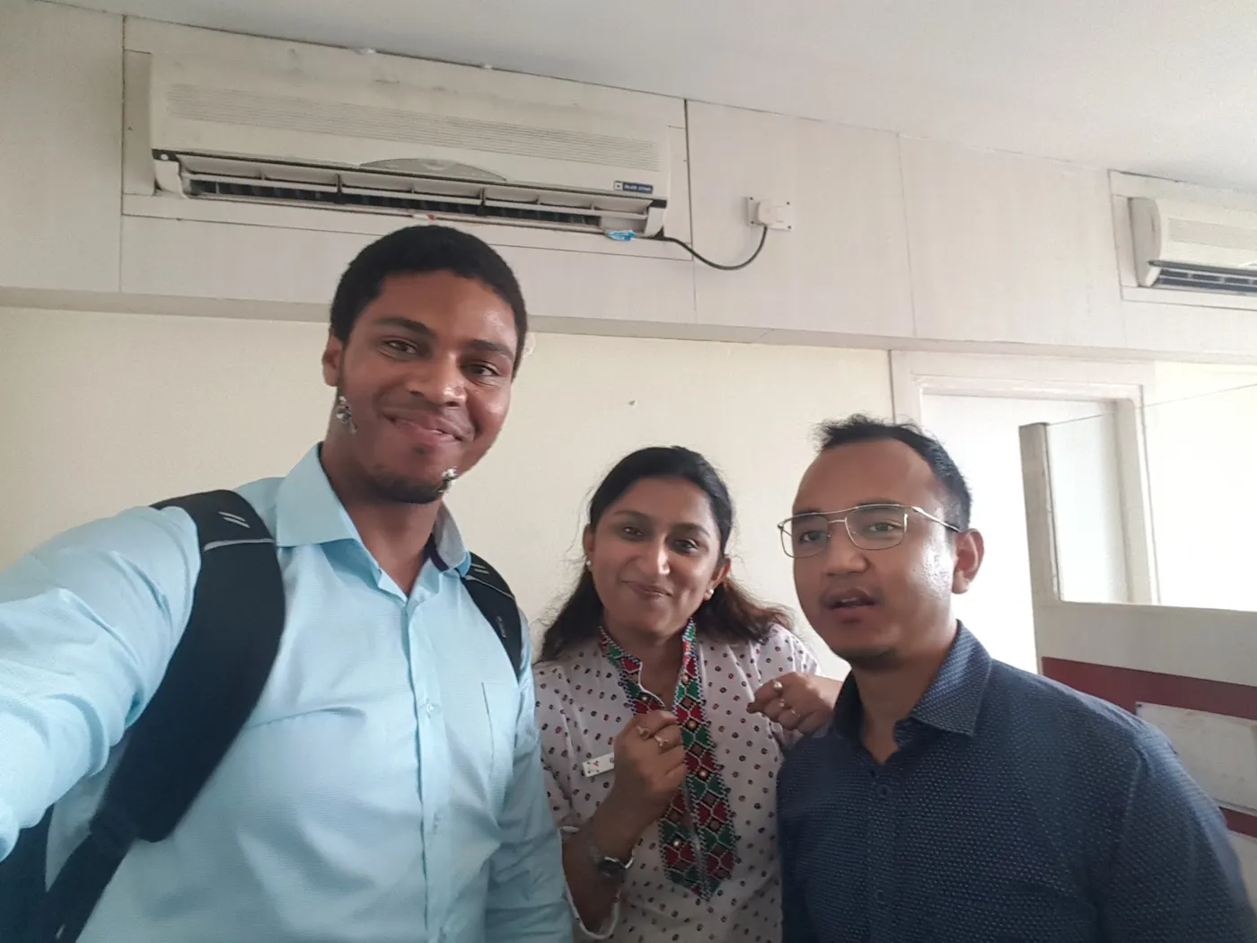 Neil taking a selfie with two colleagues in an office in India